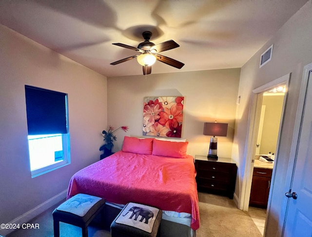 bedroom featuring ceiling fan, light colored carpet, and ensuite bath