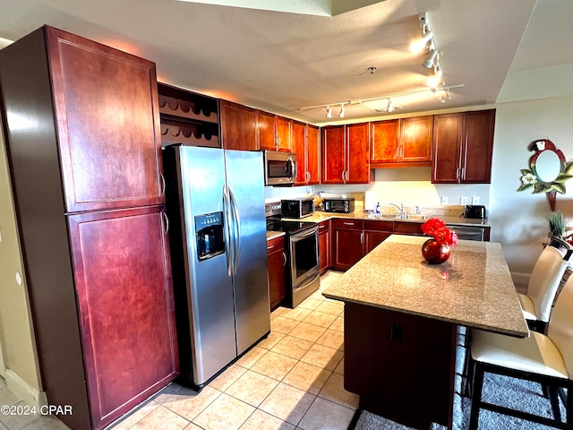 kitchen featuring light tile patterned floors, appliances with stainless steel finishes, a center island, a breakfast bar, and sink