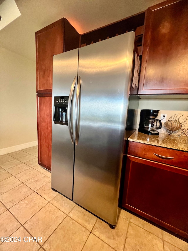 kitchen featuring stainless steel fridge with ice dispenser, light tile patterned floors, and light stone countertops