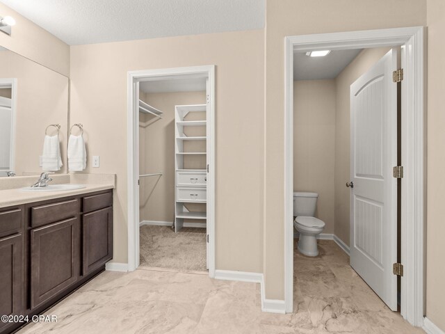 bathroom featuring vanity, a textured ceiling, and toilet