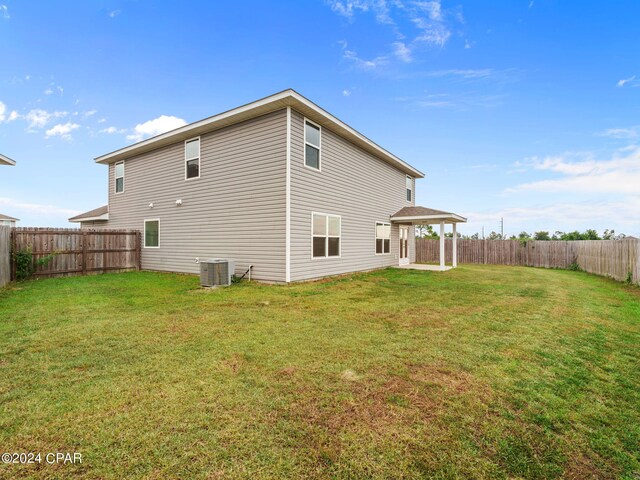 rear view of house featuring cooling unit and a lawn