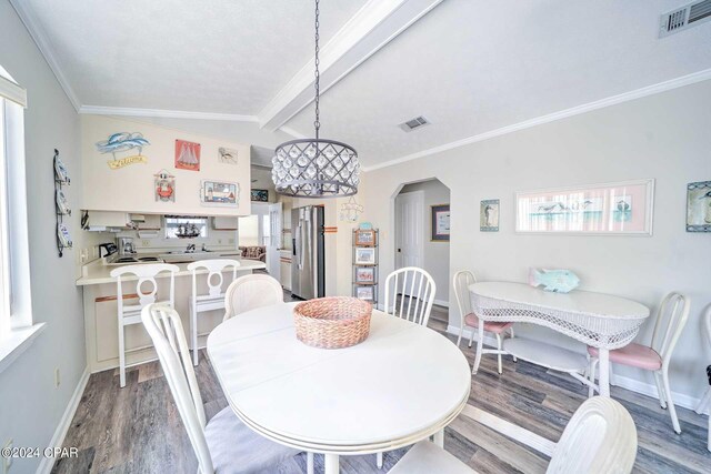 dining room featuring wood-type flooring, vaulted ceiling with beams, crown molding, and plenty of natural light