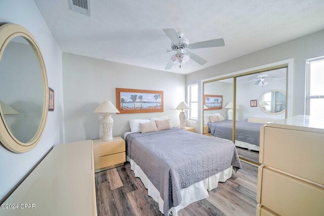 bedroom featuring hardwood / wood-style floors, a closet, multiple windows, and ceiling fan