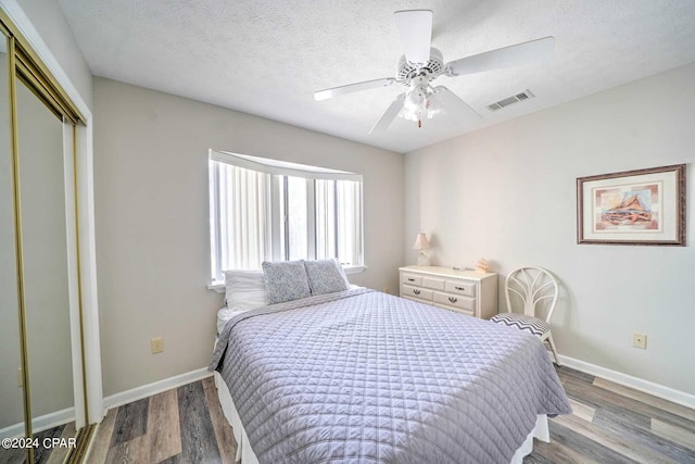 bedroom with a closet, light hardwood / wood-style floors, ceiling fan, and a textured ceiling