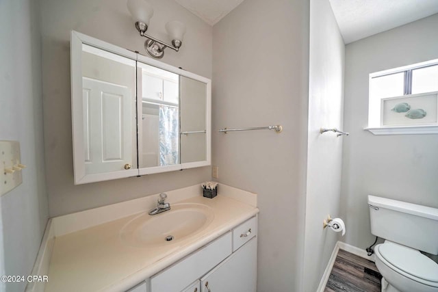 bathroom with a textured ceiling, wood-type flooring, vanity, and toilet