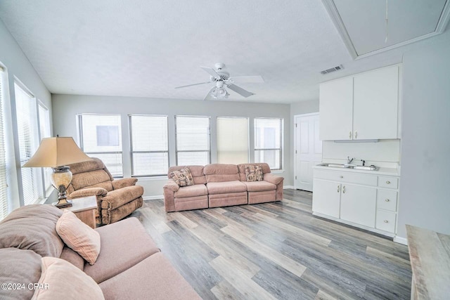 living room featuring ceiling fan, sink, light hardwood / wood-style floors, and a healthy amount of sunlight