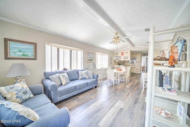 living room with ceiling fan, vaulted ceiling with beams, hardwood / wood-style flooring, and crown molding