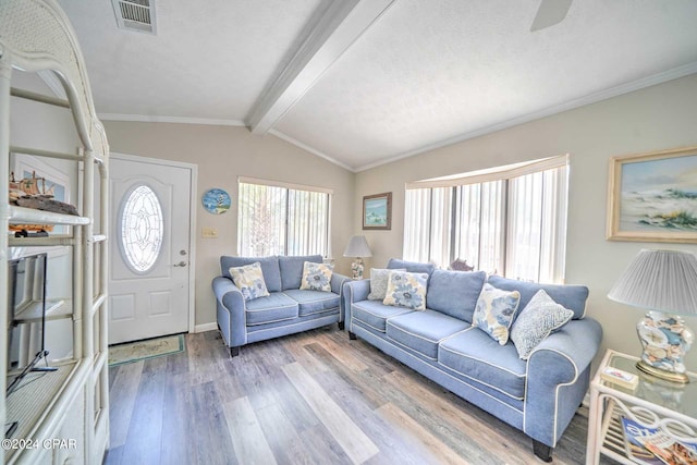 living room with a textured ceiling, light wood-type flooring, lofted ceiling with beams, and ornamental molding