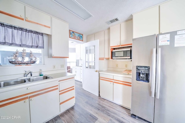 kitchen featuring a textured ceiling, light hardwood / wood-style flooring, stainless steel appliances, and white cabinets