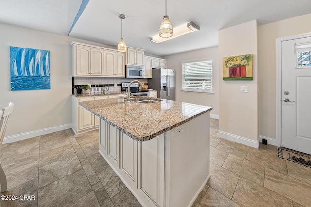 kitchen featuring pendant lighting, backsplash, sink, light stone counters, and stainless steel appliances