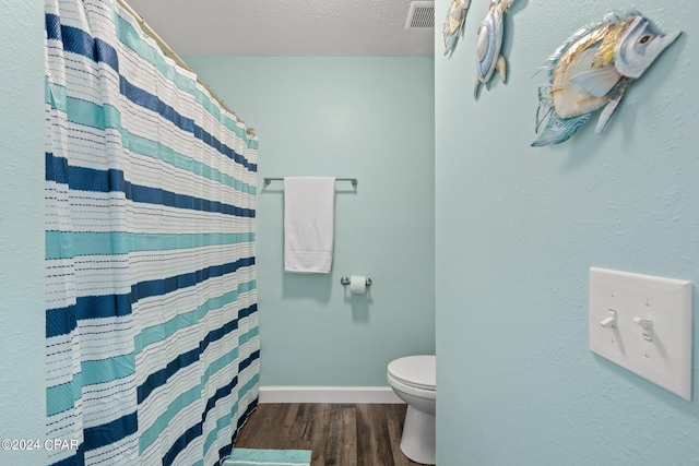 bathroom featuring a shower with curtain, a textured ceiling, hardwood / wood-style flooring, and toilet