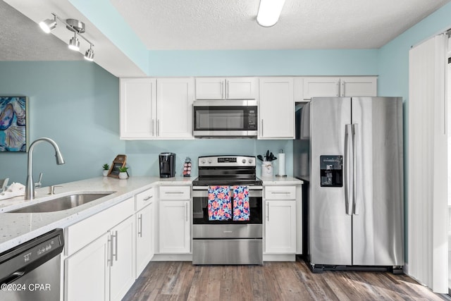 kitchen with appliances with stainless steel finishes, white cabinets, a textured ceiling, dark hardwood / wood-style floors, and sink