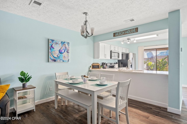 dining space featuring a textured ceiling, dark hardwood / wood-style floors, and a notable chandelier