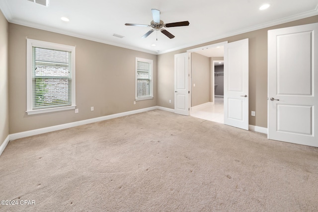 unfurnished bedroom with a walk in closet, ceiling fan, light colored carpet, and crown molding