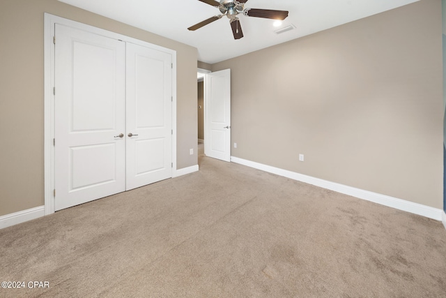 unfurnished bedroom featuring a closet, ceiling fan, and light carpet