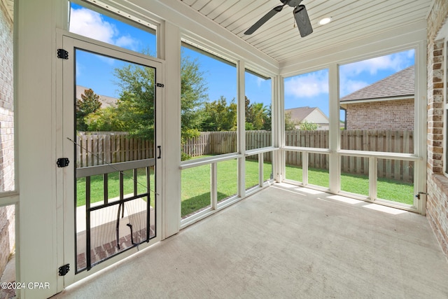 unfurnished sunroom featuring ceiling fan, wood ceiling, and plenty of natural light