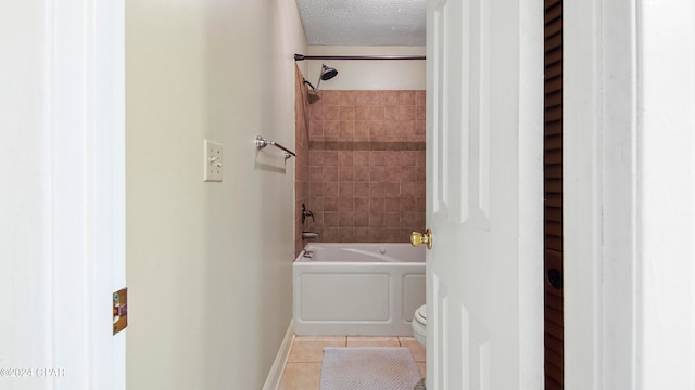 bathroom with tile patterned floors, toilet, tiled shower / bath combo, and a textured ceiling