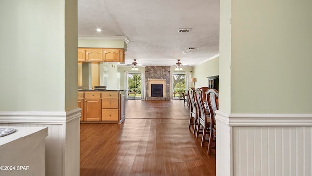 kitchen with a fireplace, crown molding, light brown cabinets, dark wood-type flooring, and ceiling fan