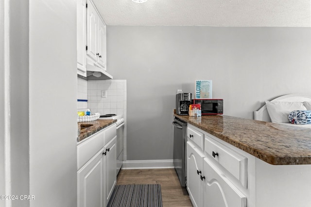 kitchen featuring dark hardwood / wood-style flooring, white cabinets, tasteful backsplash, kitchen peninsula, and dark stone counters