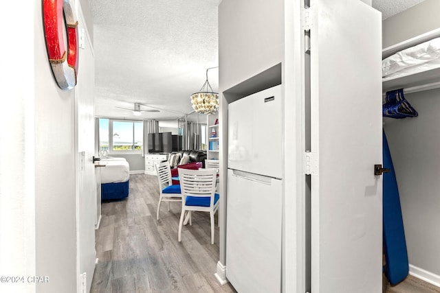 corridor featuring a textured ceiling, hardwood / wood-style flooring, and a notable chandelier