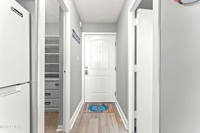 doorway featuring a textured ceiling and light wood-type flooring