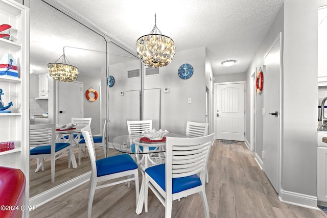 dining area with a textured ceiling, hardwood / wood-style flooring, and a chandelier