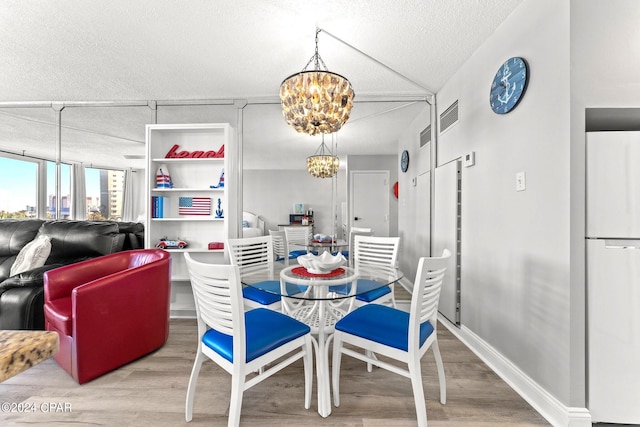 dining room featuring lofted ceiling, hardwood / wood-style floors, an inviting chandelier, and a textured ceiling