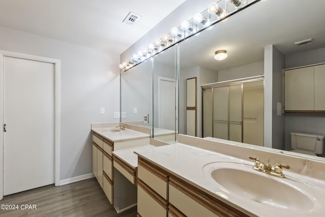 bathroom featuring hardwood / wood-style floors, toilet, a shower with door, and vanity