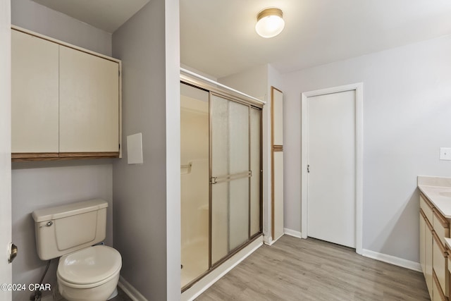 bathroom featuring vanity, toilet, wood-type flooring, and a shower with door