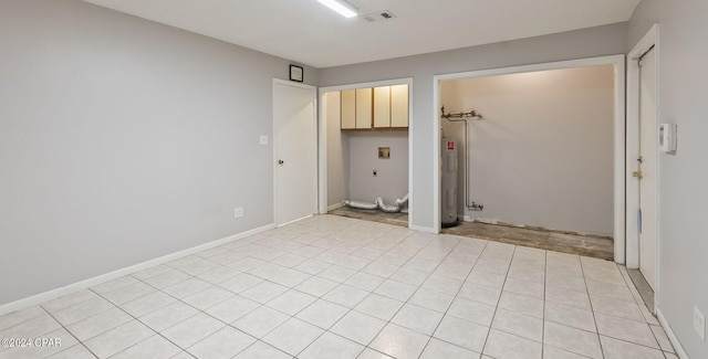 unfurnished room featuring light tile patterned floors and water heater