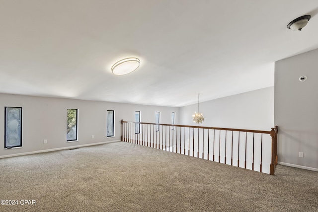 carpeted empty room with a chandelier