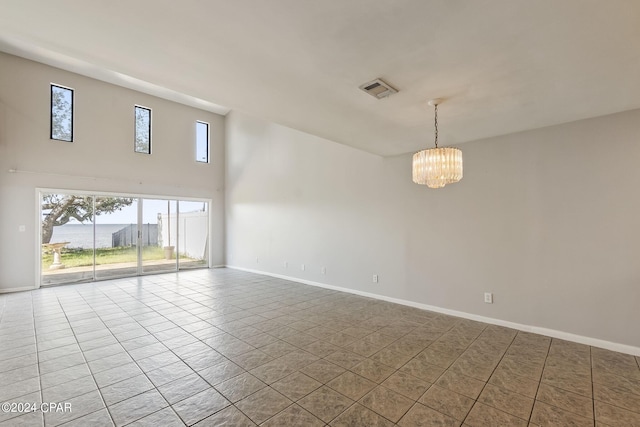 empty room with tile patterned flooring and a notable chandelier