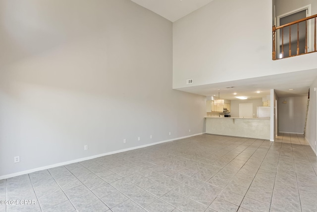 unfurnished living room with light tile patterned floors and a towering ceiling