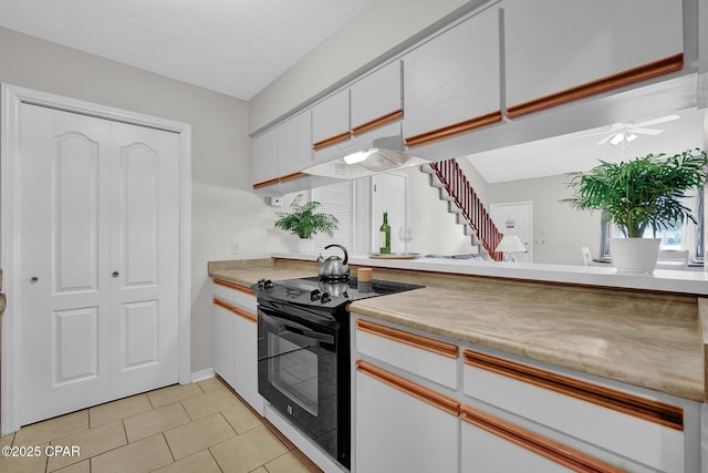 kitchen featuring light tile patterned flooring, black electric range oven, a textured ceiling, ceiling fan, and white cabinets