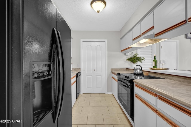 kitchen with light tile patterned floors, black appliances, a textured ceiling, white cabinets, and exhaust hood