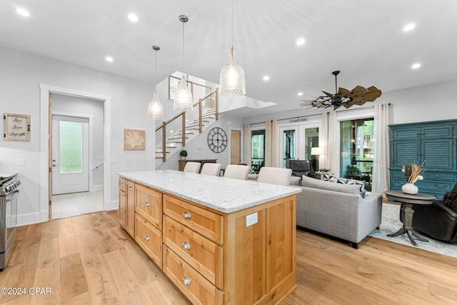 kitchen featuring light stone countertops, ceiling fan, a center island, light hardwood / wood-style flooring, and pendant lighting