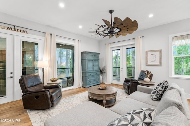 living area with recessed lighting, wood finished floors, a healthy amount of sunlight, and french doors