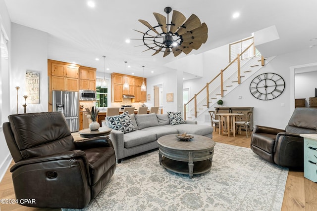 living area featuring light wood finished floors, a ceiling fan, stairway, and recessed lighting