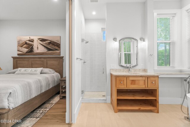 bedroom featuring connected bathroom, light hardwood / wood-style flooring, and sink