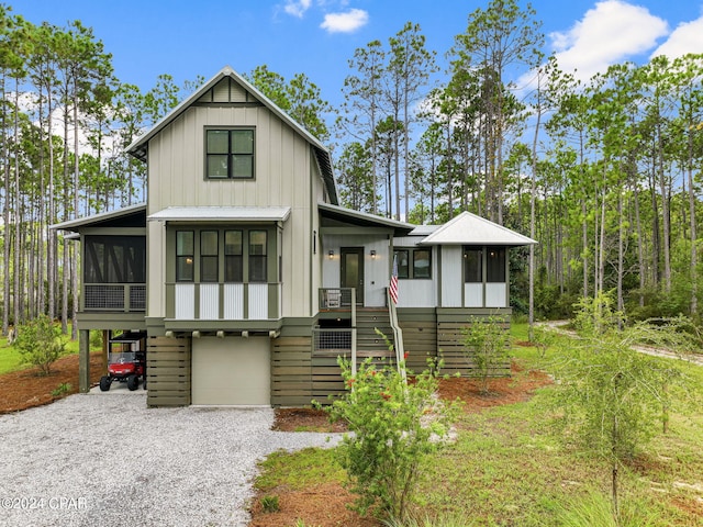 modern farmhouse featuring driveway, stairs, an attached garage, and a sunroom