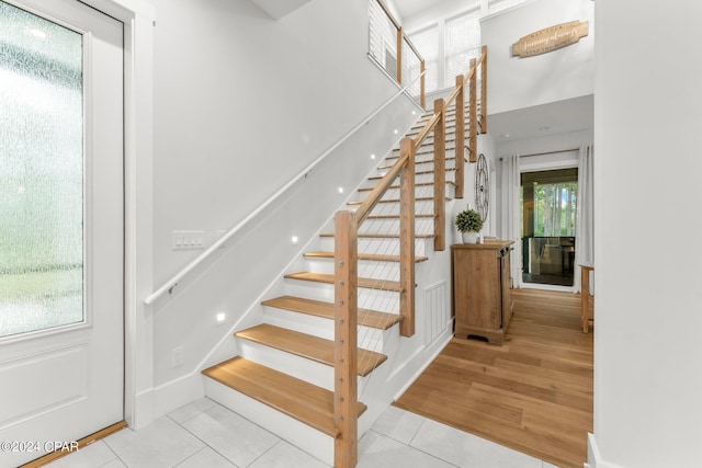 staircase with tile patterned floors and a towering ceiling