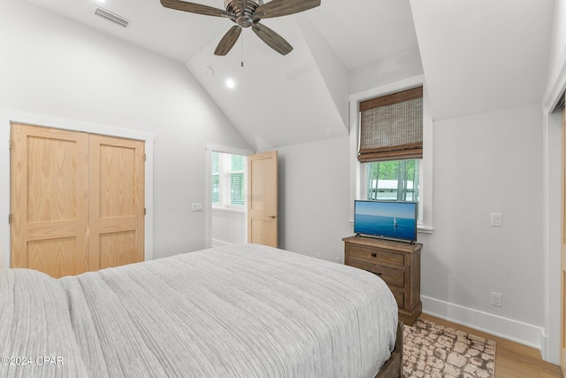 bedroom featuring lofted ceiling, visible vents, light wood-style floors, baseboards, and a ceiling fan