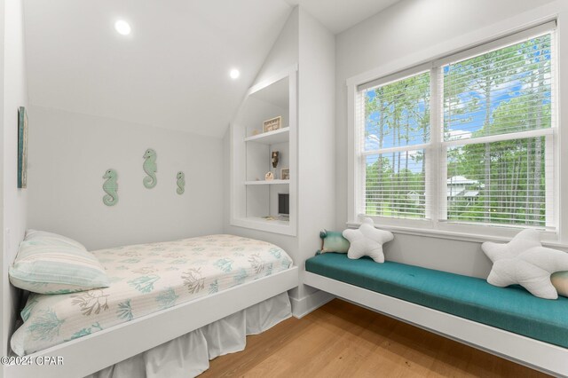 bedroom with hardwood / wood-style flooring, vaulted ceiling, and multiple windows