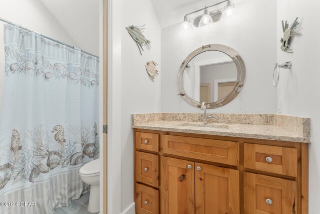 bathroom with a shower with shower curtain, tile patterned floors, vanity, vaulted ceiling, and toilet