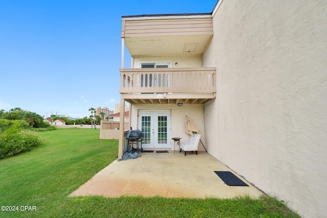 rear view of house featuring a balcony, a yard, and a patio