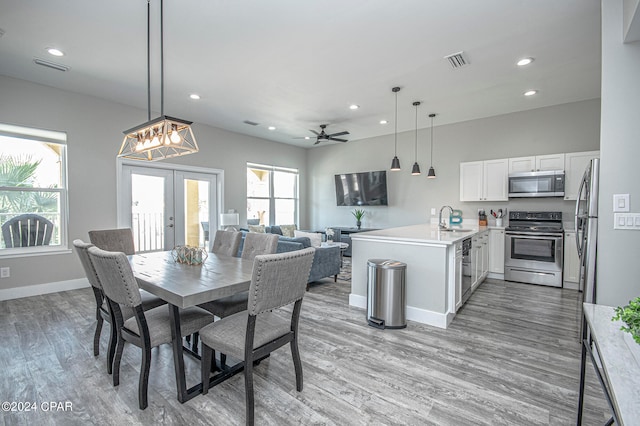 dining area featuring sink, ceiling fan with notable chandelier, french doors, and light hardwood / wood-style floors