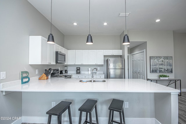 kitchen featuring stainless steel appliances, sink, a kitchen breakfast bar, kitchen peninsula, and pendant lighting