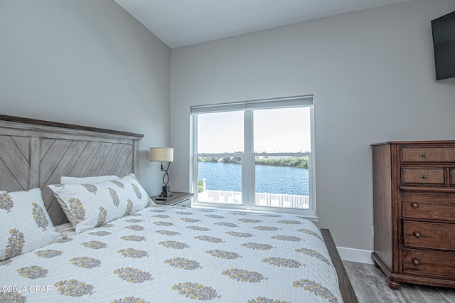 bedroom featuring vaulted ceiling, a water view, and hardwood / wood-style floors