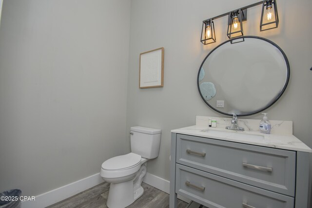 112 Riviera Dr, Panama City Beach, FL 32413 - half bathroom featuring baseboards, vanity, wood finished floors, and toilet