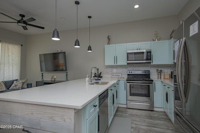112 Riviera Dr, Panama City Beach, FL 32413 - kitchen with stainless steel appliances, a sink, a ceiling fan, light wood-style floors, and a peninsula